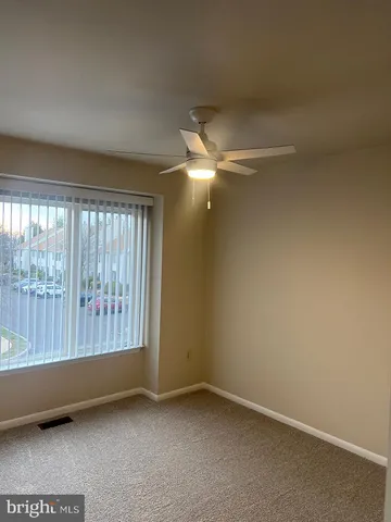 an empty room with a ceiling fan and a window