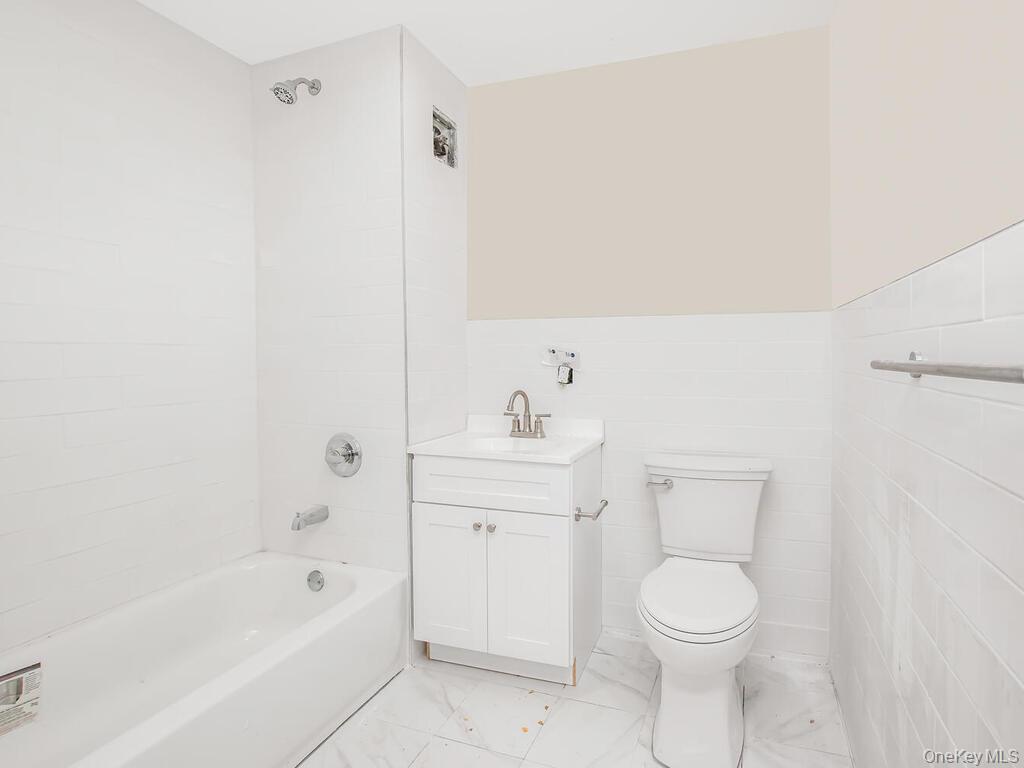 409 Warburton Avenue, Unit 2B Yonkers, NY 10701 - Photo 2 of 4 a bathroom with a toilet a sink a mirror and vanity
