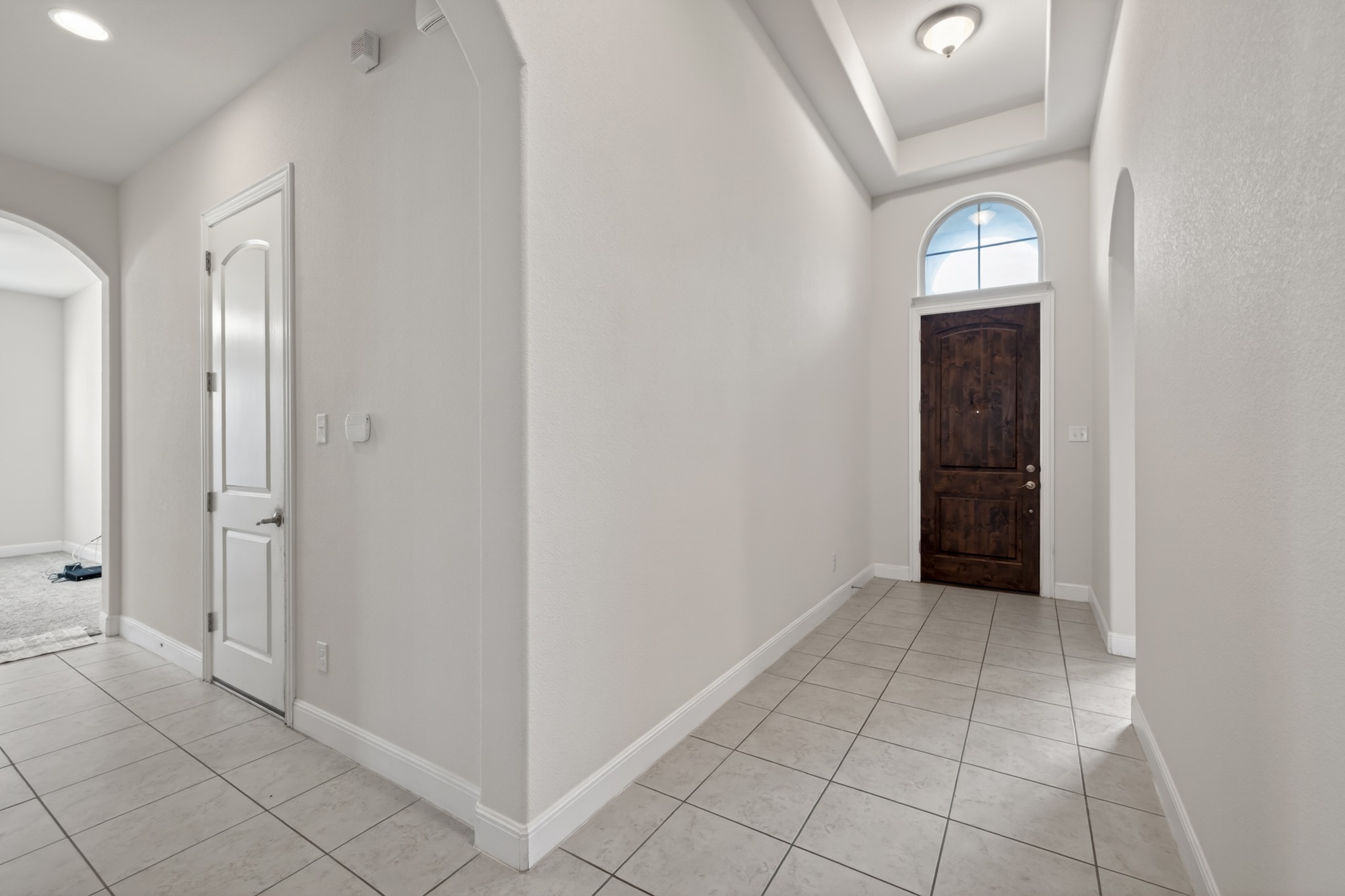 1017 Tabernash Leander, TX 78641 - Photo 5 of 38 Entryway featuring a rich wood-finish door with an arched transom window, a tray ceiling with a flush-mount light fixture, and ceramic tile flooring