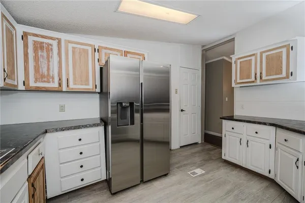 a kitchen with granite countertop white cabinets and refrigerator