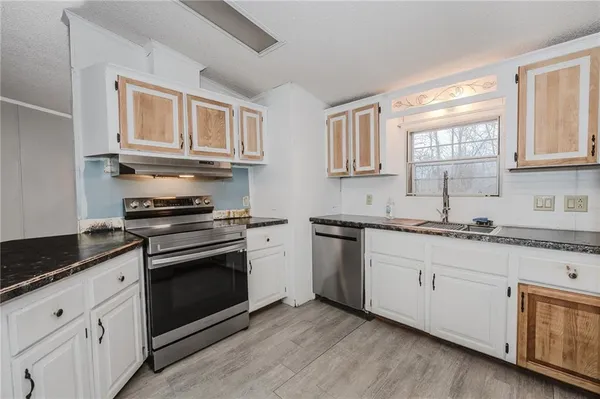 a kitchen with granite countertop cabinets stainless steel appliances a sink and a window
