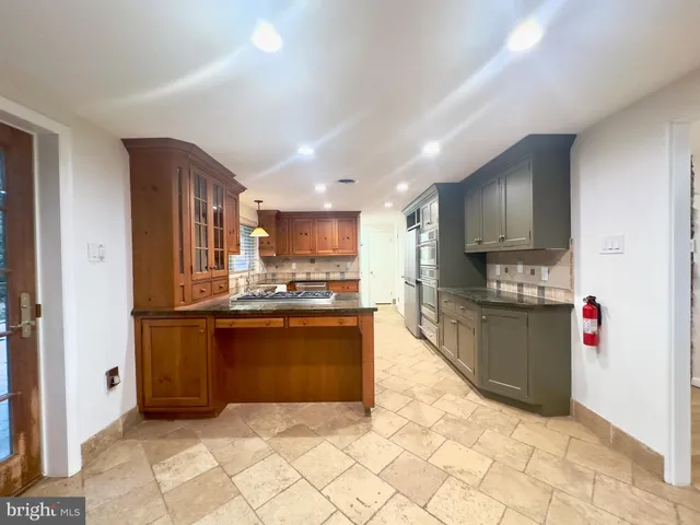 a large kitchen with stainless steel appliances kitchen island granite countertop a refrigerator and a sink