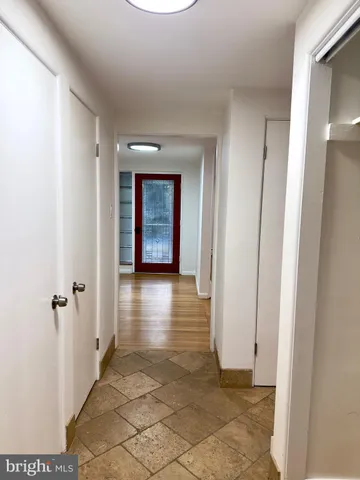 a view of a hallway with wooden floor and a bathroom
