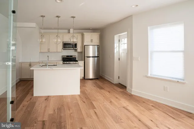 a kitchen with stainless steel appliances granite countertop a refrigerator a stove and a wooden floors