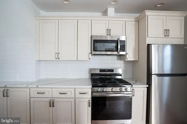a kitchen with cabinets stainless steel appliances and a counter space