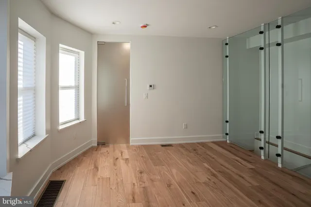 a view of an empty room with wooden floor and a window