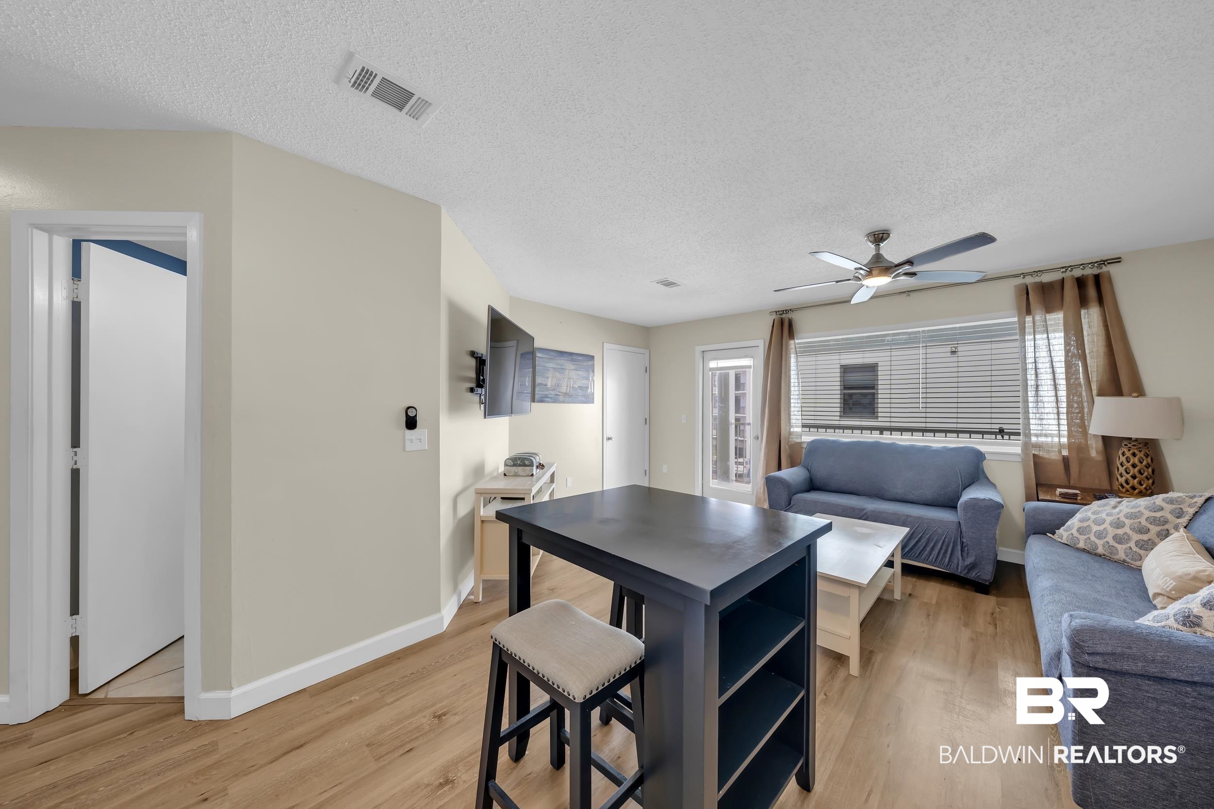 27222 Gulf Road, Unit 33 Orange Beach, AL 36561 - Photo 17 of 29 Living area featuring wood-finish flooring, a ceiling fan with integrated lighting, and neutral wall tones