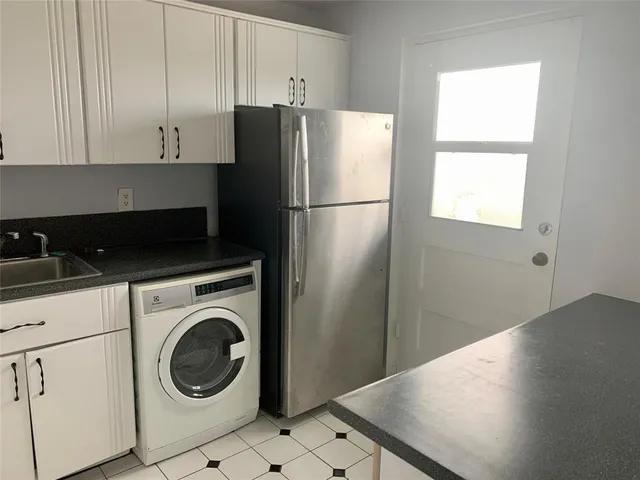 a kitchen with a refrigerator and white cabinets