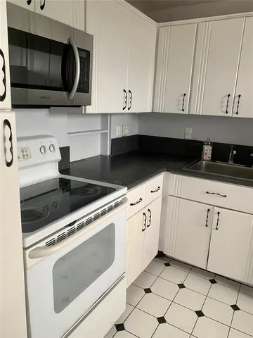 a kitchen with granite countertop white cabinets stainless steel appliances and sink