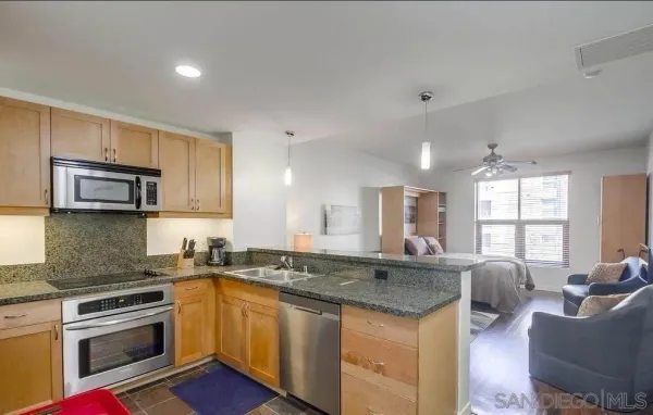 a kitchen with stainless steel appliances granite countertop a stove a sink dishwasher a refrigerator and white cabinets with wooden floor