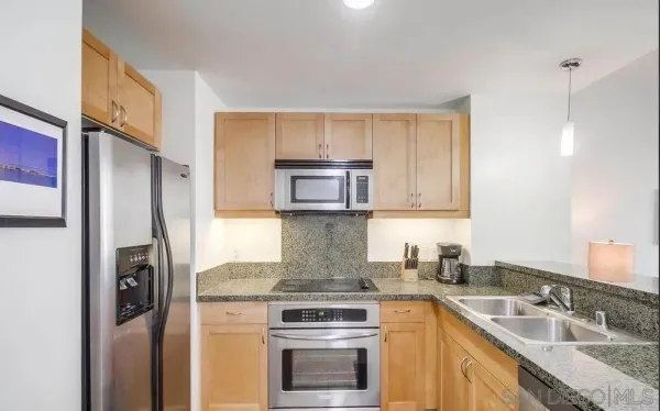 a kitchen with stainless steel appliances granite countertop a refrigerator a stove and a sink with wooden floor