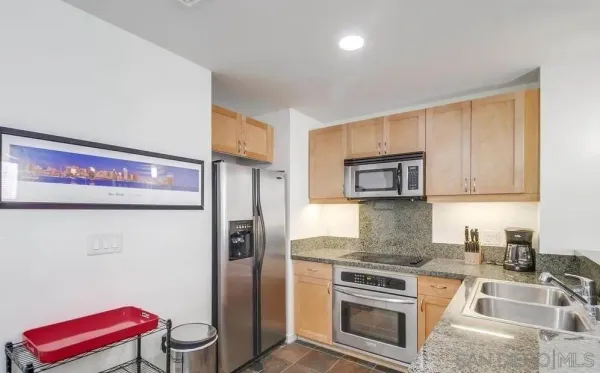 a kitchen with stainless steel appliances granite countertop a refrigerator sink and stove
