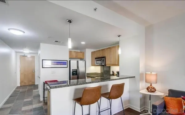 a kitchen with stainless steel appliances kitchen island granite countertop a refrigerator a stove a oven with white cabinets and chairs