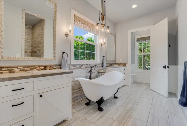 a spacious bathroom with a double vanity sink a mirror and a bathtub