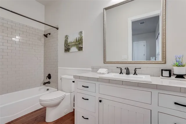 a bathroom with a granite countertop toilet sink a mirror a bathtub and shower