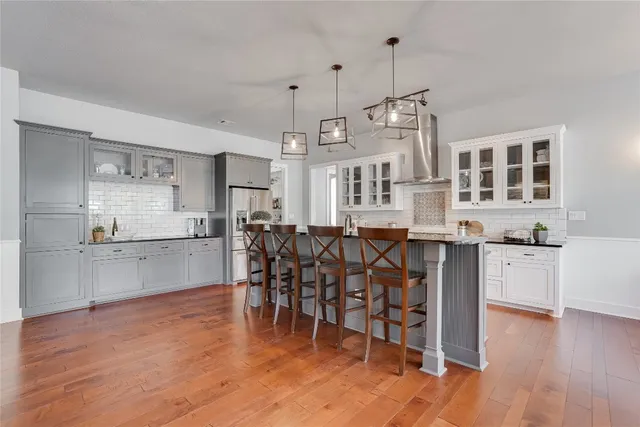 a open kitchen with stainless steel appliances granite countertop a stove top oven a sink dishwasher and a dining table with wooden floor