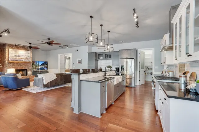 a large white kitchen with lots of counter top space and stainless steel appliances