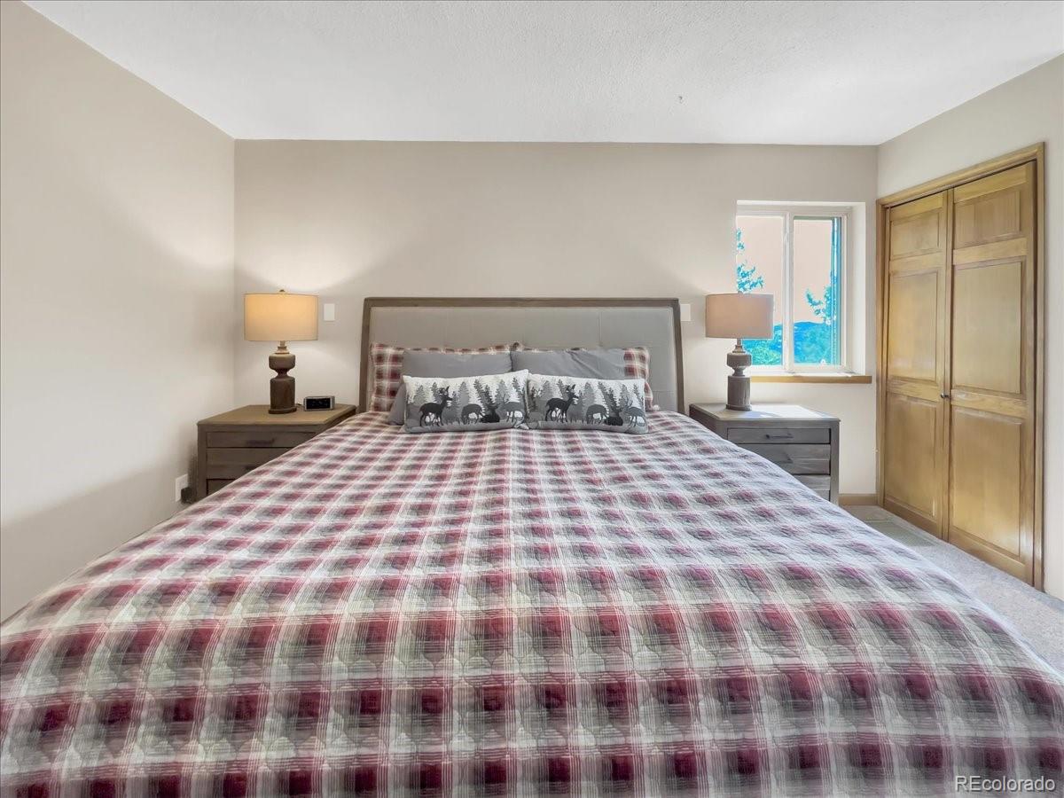 22155 Cook Lane Morrison, CO 80465 - Photo 15 of 28 a bedroom with a large bed and a lamp on dresser