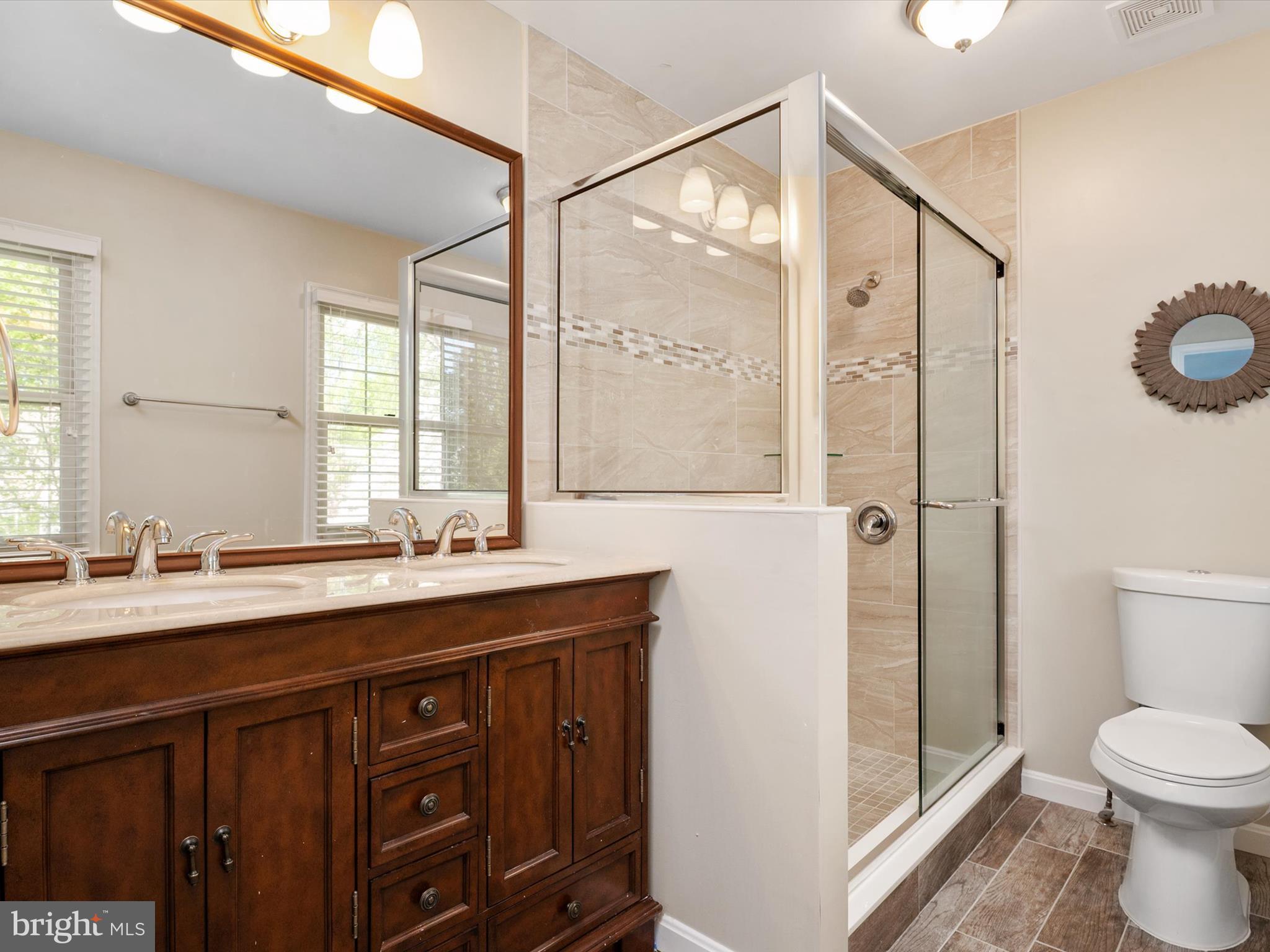1711 Peartree Lane Crofton, MD 21114 - Photo 31 of 65 a bathroom with a double vanity sink toilet mirror and shower