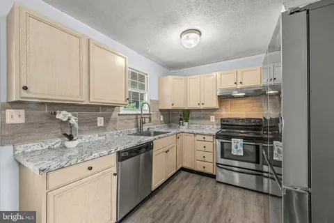 a kitchen with stainless steel appliances granite countertop a stove a sink and white cabinets