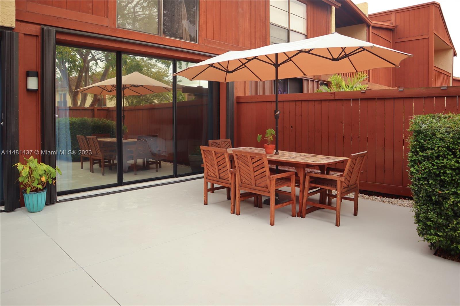 6704 Southwest 114th Place, Unit E Miami, FL 33173 - Photo 23 of 34 a view of a patio with a table and chairs under an umbrella