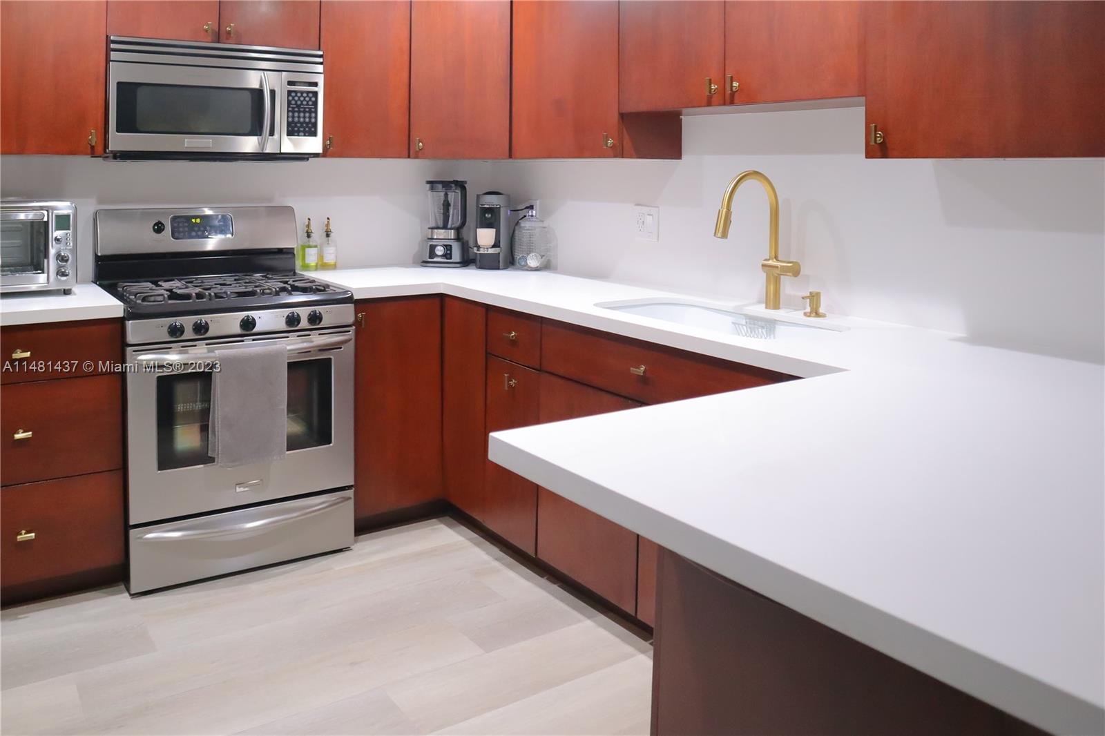 6704 Southwest 114th Place, Unit E Miami, FL 33173 - Photo 5 of 34 a kitchen with stainless steel appliances a stove microwave and sink