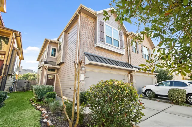 a front view of a residential apartment building with yard and parking