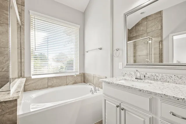 a bathroom with a granite countertop sink and a bathtub