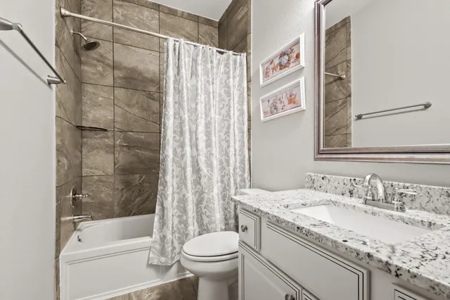 a bathroom with a granite countertop sink a toilet and a bathtub