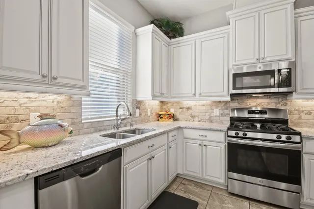 a kitchen with granite countertop a sink cabinets and stainless steel appliances