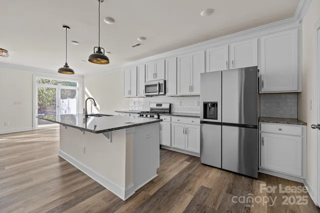 a kitchen with stainless steel appliances granite countertop a refrigerator a stove a sink dishwasher and a refrigerator with wooden floor