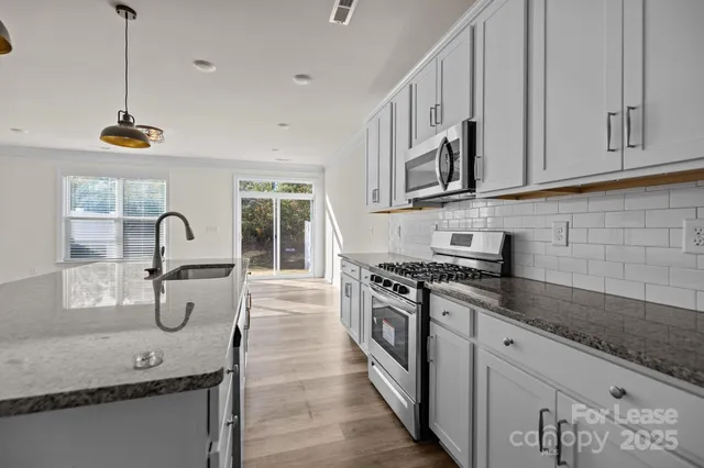 a kitchen with stainless steel appliances granite countertop a sink a stove and a wooden floors
