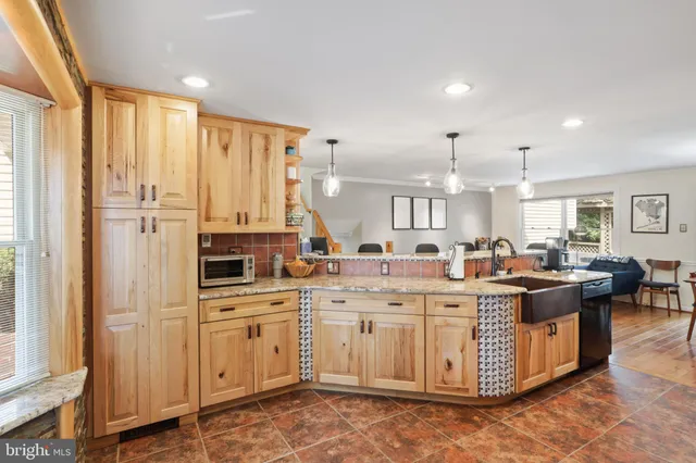 a large white kitchen with a stove a sink dishwasher and a dining table with wooden floor