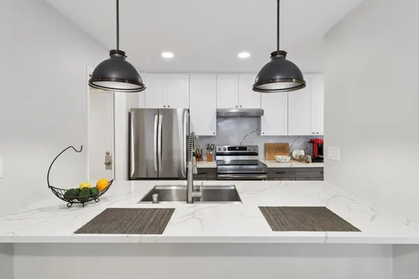 a kitchen with stainless steel appliances granite countertop a stove a refrigerator and a sink with wooden floor