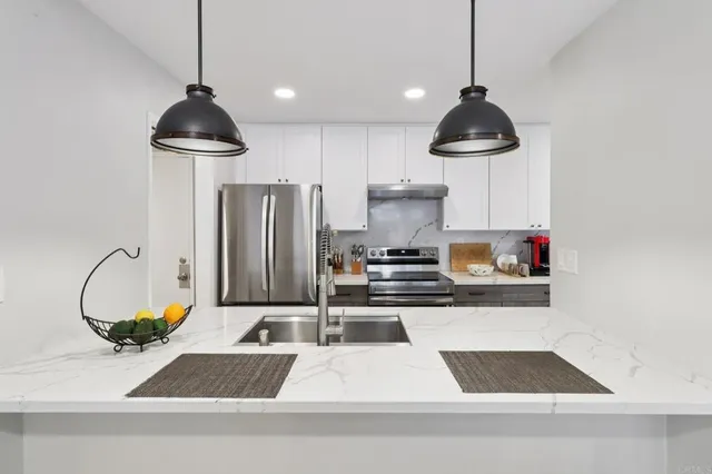 a kitchen with stainless steel appliances granite countertop a stove a refrigerator and a sink with wooden floor