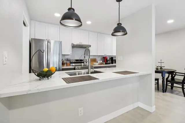 a kitchen with stainless steel appliances a sink a stove a refrigerator and cabinets