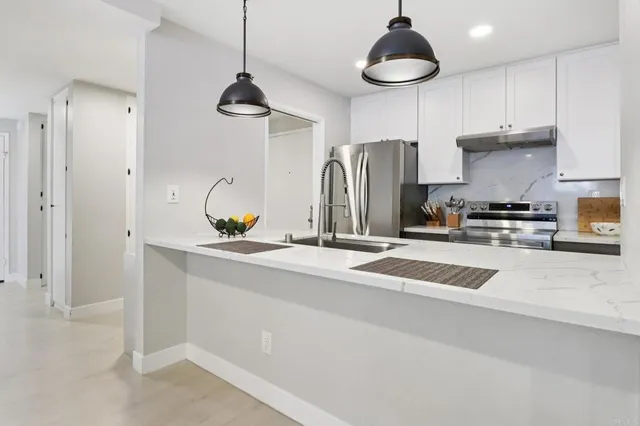 a kitchen with stainless steel appliances granite countertop a sink a refrigerator and a granite counter tops