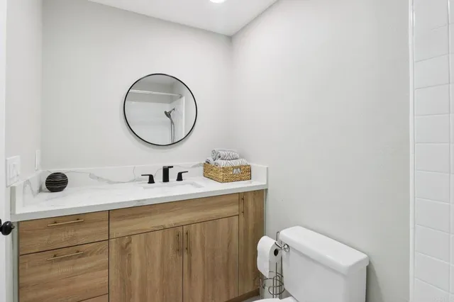 a bathroom with a toilet sink vanity and mirror