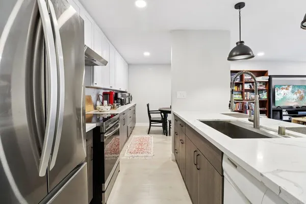 a kitchen with stainless steel appliances granite countertop a refrigerator a sink and a stove