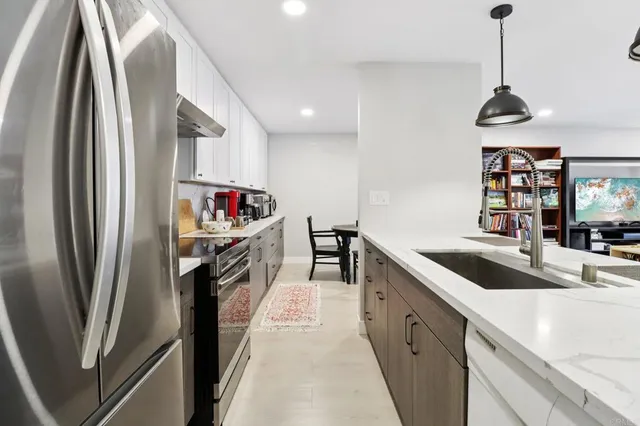 a kitchen with stainless steel appliances granite countertop a refrigerator a sink and a stove