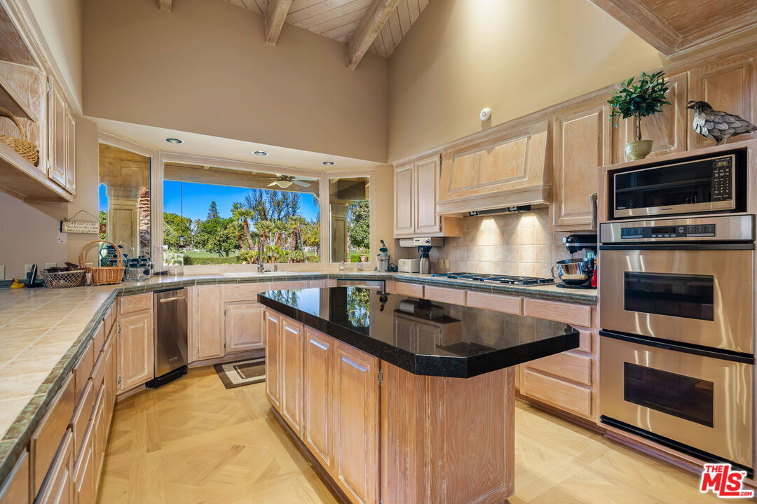 71150 North Thunderbird Terrace Rancho Mirage, CA 92270 - Photo 32 of 75 a kitchen with stainless steel appliances granite countertop a sink a stove and a microwave oven