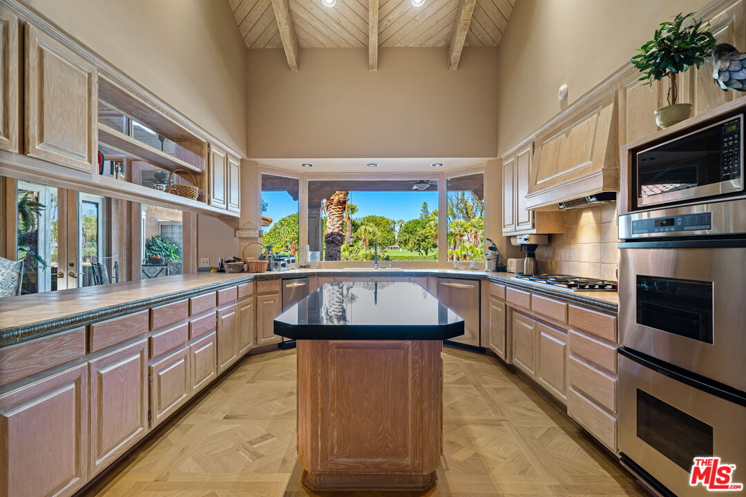 71150 North Thunderbird Terrace Rancho Mirage, CA 92270 - Photo 33 of 75 a kitchen with stainless steel appliances granite countertop a stove a sink and a microwave
