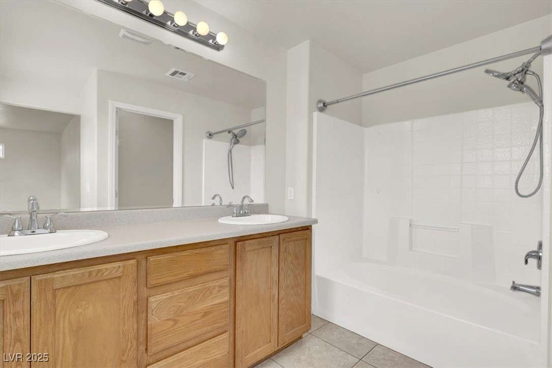 6909 Graceful Cloud Avenue Las Vegas, NV 89122 - Photo 25 of 33 Full bath with light tile patterned floors, double vanity, and shower combination