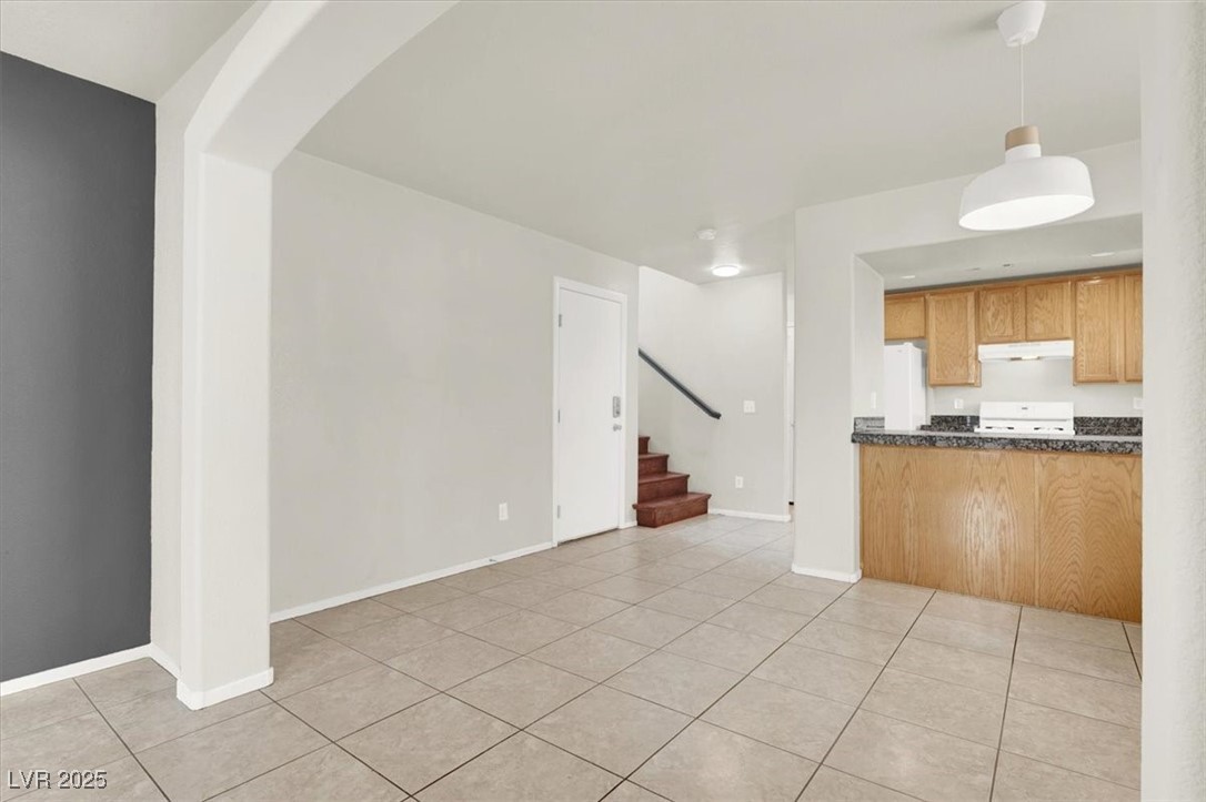 6909 Graceful Cloud Avenue Las Vegas, NV 89122 - Photo 4 of 33 Unfurnished living room with light tile patterned floors, stairs, and arched walkways