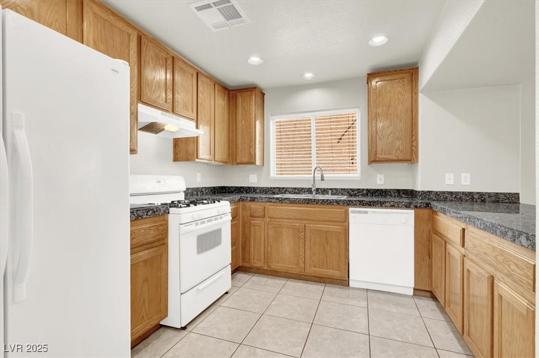 6909 Graceful Cloud Avenue Las Vegas, NV 89122 - Photo 7 of 33 Kitchen featuring white appliances, light tile patterned floors, recessed lighting, under cabinet range hood, and brown cabinets