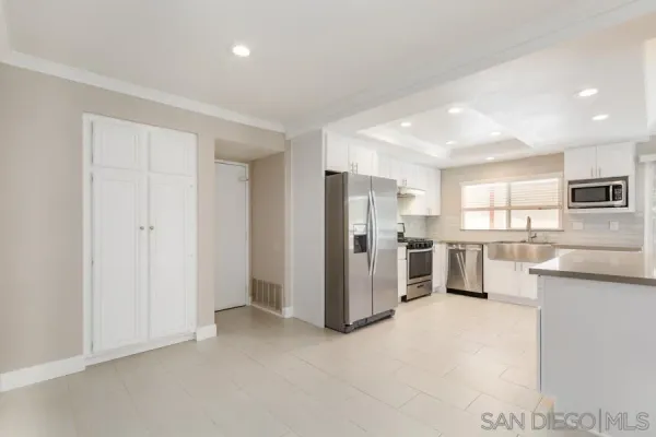 a view of a kitchen with refrigerator and white cabinets