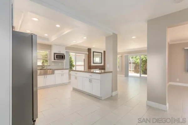 a large white kitchen with a sink and dishwasher a refrigerator with white cabinets