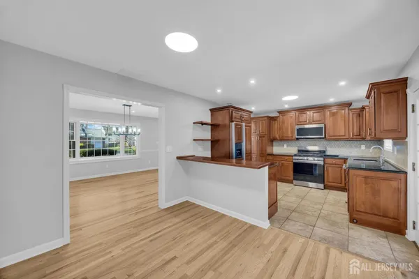 a large kitchen with stainless steel appliances granite countertop a sink a stove and a refrigerator