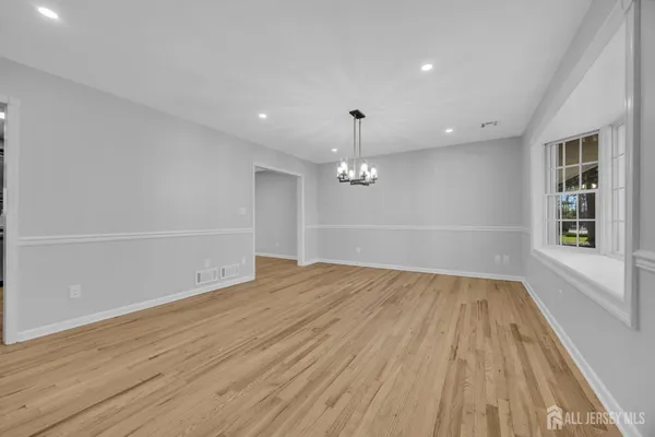 an empty room with wooden floor cabinet and windows