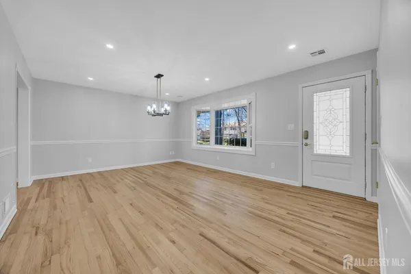 a view of empty room with wooden floor and kitchen